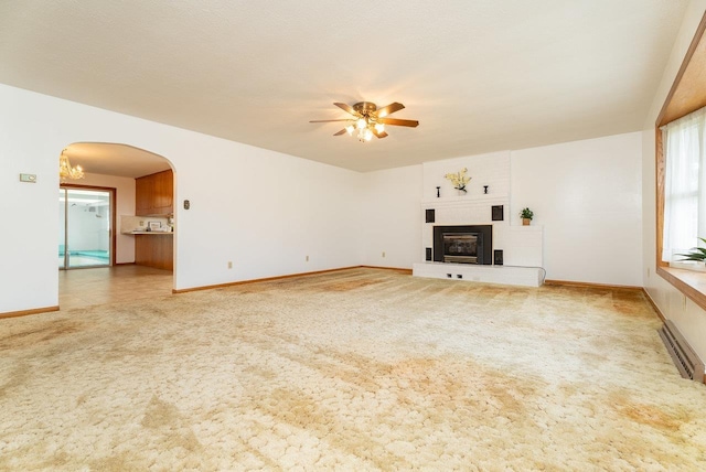 4490 N Valley Pike, Rockingham, VA 22802 - unfurnished living room featuring light colored carpet, arched walkways, ceiling fan, and a large fireplace