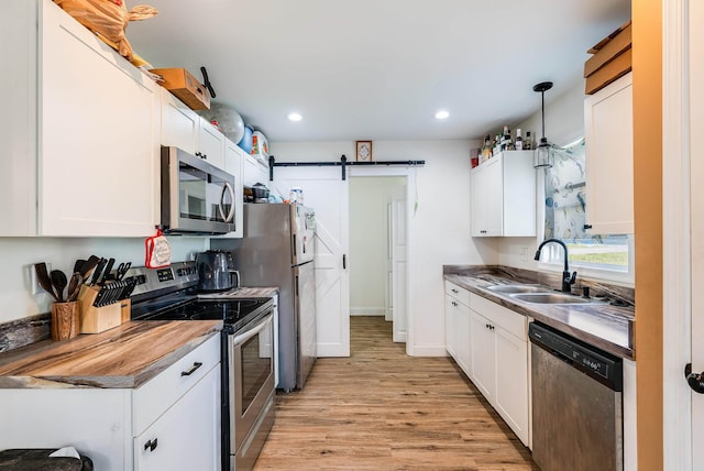 250 Washington Ave W, Elkton, VA 22827 - kitchen with appliances with stainless steel finishes, a sink, a barn door, light wood finished floors, and white cabinets