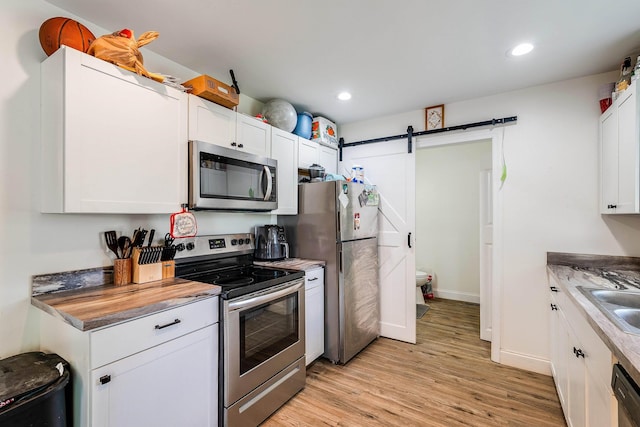 250 Washington Ave W, Elkton, VA 22827 - kitchen with appliances with stainless steel finishes, a barn door, light wood-type flooring, white cabinetry, and recessed lighting