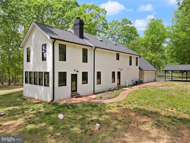  - rear view of property with cooling unit, a yard, a chimney, and entry steps