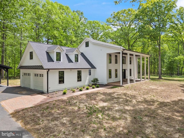  - view of front facade with covered porch, roof with shingles, a garage, and decorative driveway