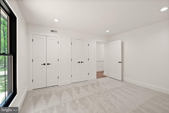  - unfurnished bedroom featuring two closets, carpet flooring, visible vents, and recessed lighting