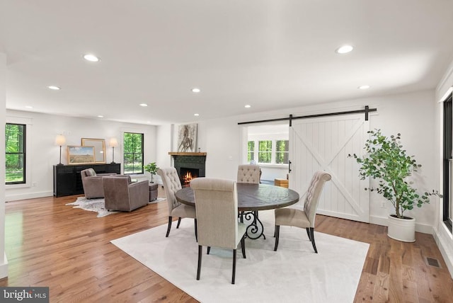  - dining space with a barn door, visible vents, recessed lighting, light wood-style flooring, and a brick fireplace