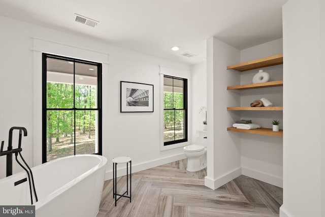  - full bath with a freestanding bath, toilet, baseboards, and visible vents