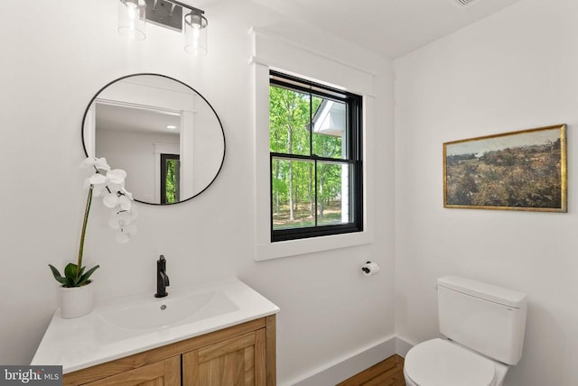  - bathroom featuring toilet, baseboards, vanity, and wood finished floors