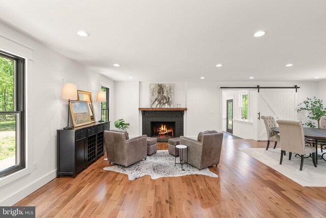  - living area featuring a brick fireplace, a barn door, light wood-type flooring, and recessed lighting