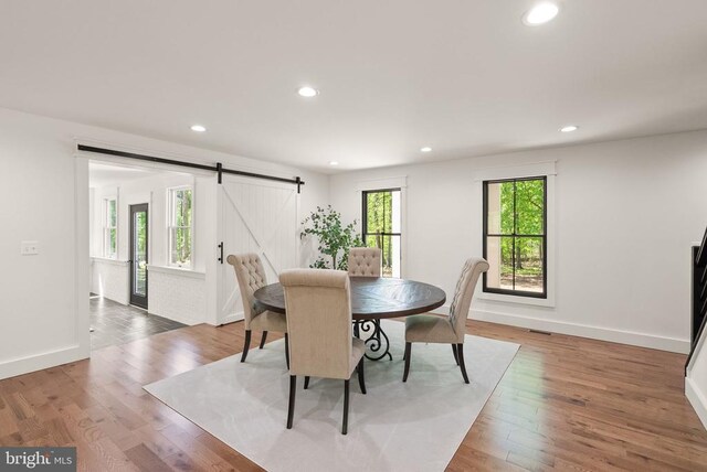  - dining room featuring light wood finished floors, a barn door, baseboards, and recessed lighting