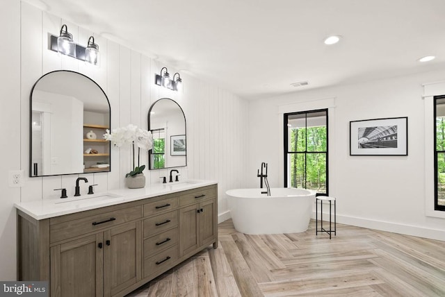  - full bath featuring a soaking tub, visible vents, baseboards, and a sink