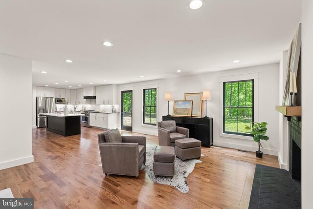  - living area with a healthy amount of sunlight, a brick fireplace, and recessed lighting