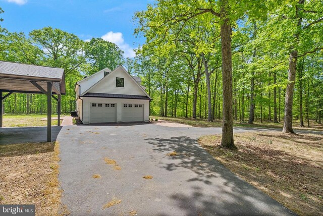  - view of side of property featuring an outdoor structure, metal roof, a standing seam roof, and aphalt driveway