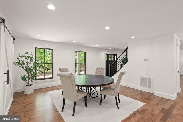  - dining space with light wood-style flooring, recessed lighting, a barn door, baseboards, and visible vents