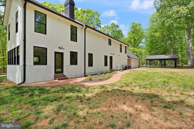  - rear view of house with a chimney, entry steps, central AC unit, and a lawn