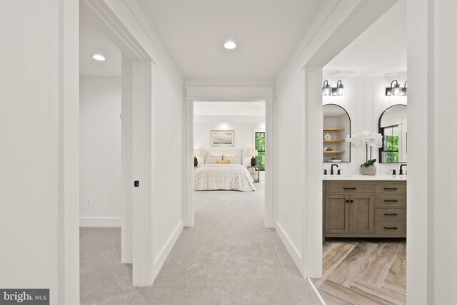  - hallway featuring light colored carpet, recessed lighting, baseboards, and a sink