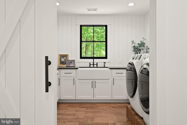  - laundry area featuring washing machine and dryer, light wood finished floors, visible vents, a sink, and cabinet space