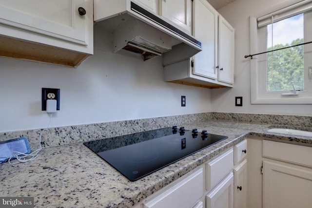 kitchen featuring black electric cooktop, under cabinet range hood, and white cabinetry