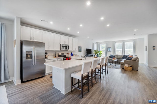 802 Wesley Ln Unit B, Charlottesville, VA 22911 - kitchen with stainless steel appliances, light wood finished floors, a center island with sink, open floor plan, and white cabinets