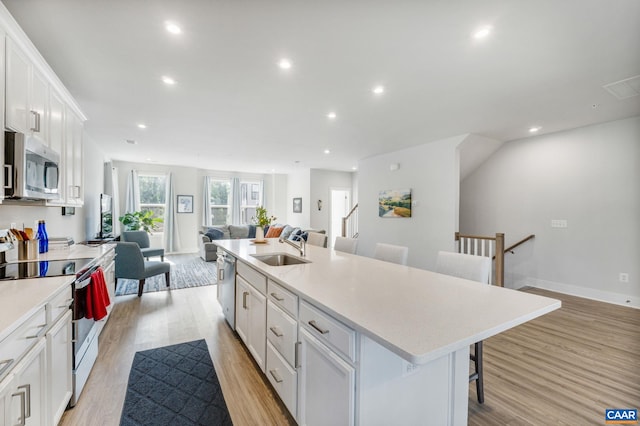 802 Wesley Ln Unit B, Charlottesville, VA 22911 - kitchen with appliances with stainless steel finishes, open floor plan, white cabinetry, a breakfast bar area, and light wood-type flooring