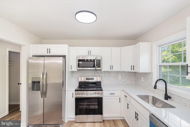 8452 Turnbull Rd, Warrenton, VA 20186 - kitchen featuring stainless steel appliances, a sink, light wood finished floors, white cabinetry, and backsplash