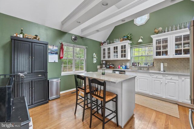 372 Daniels Rd, Barboursville, VA 22923 - kitchen with a sink, light wood-type flooring, white cabinets, tasteful backsplash, and vaulted ceiling