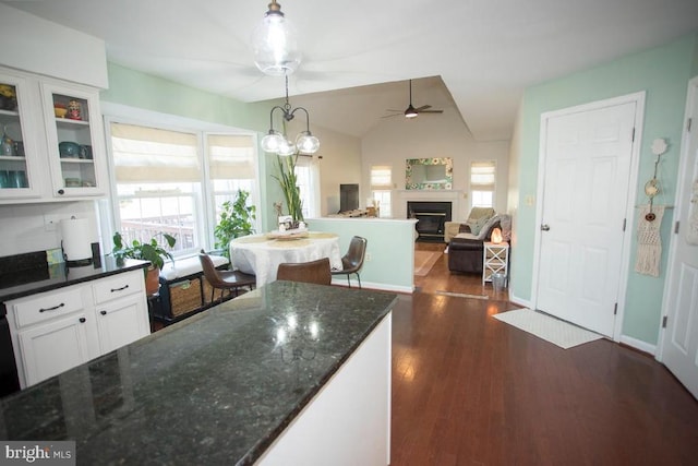 kitchen with ceiling fan, white cabinetry, a fireplace, dark wood-type flooring, and glass insert cabinets