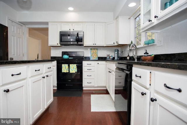 kitchen with black appliances, white cabinets, dark wood finished floors, backsplash, and a sink