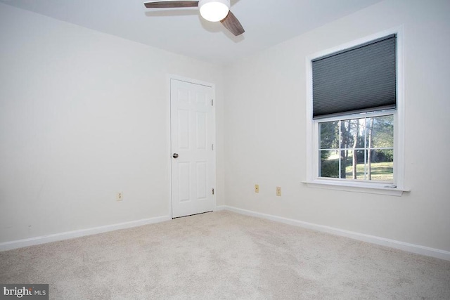 carpeted spare room with a ceiling fan and baseboards