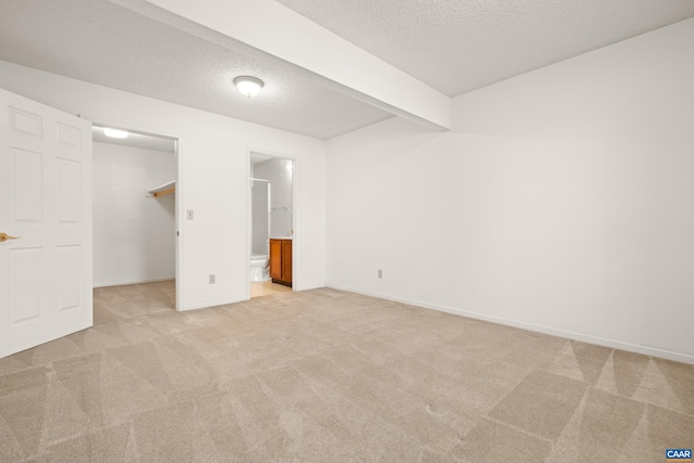 1184 Partridge Ln, Charlottesville, VA 22901 - unfurnished bedroom featuring light colored carpet, a textured ceiling, a walk in closet, baseboards, and ensuite bath