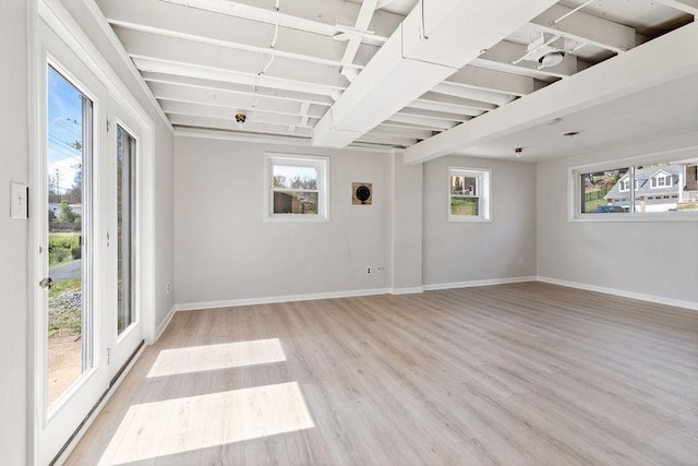 unfurnished room featuring beamed ceiling, baseboards, and light wood-type flooring