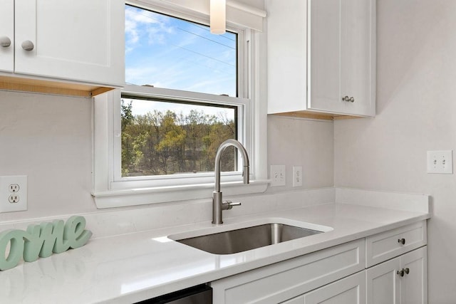 kitchen with white cabinetry, light countertops, and a sink