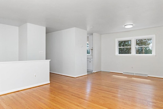empty room featuring light wood-type flooring, visible vents, and baseboards
