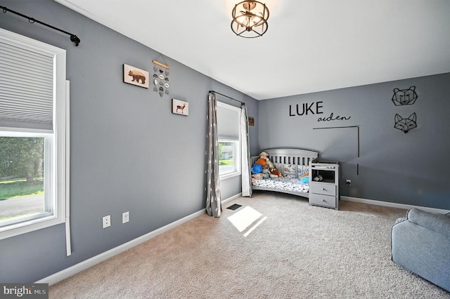  - carpeted bedroom featuring baseboards and a chandelier