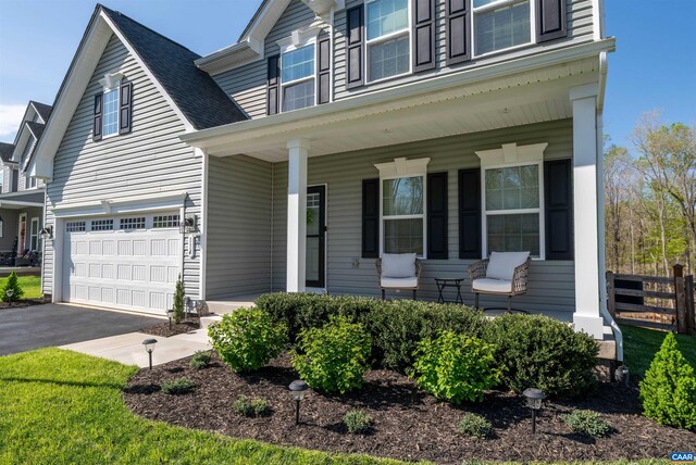 view of front of house featuring covered porch, aphalt driveway, fence, an attached garage, and a shingled roof