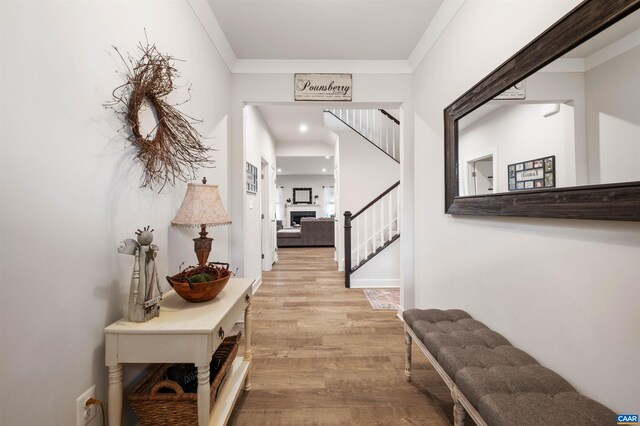 hallway featuring stairway, wood finished floors, and ornamental molding
