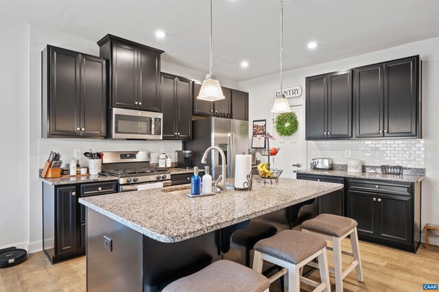 kitchen featuring stainless steel appliances, a sink, a breakfast bar, backsplash, and recessed lighting