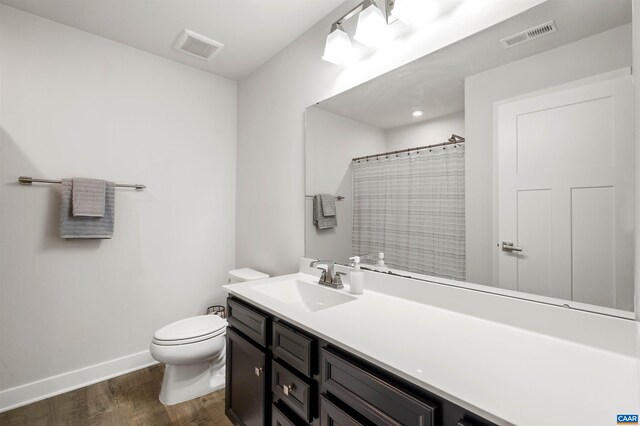 bathroom featuring toilet, wood finished floors, vanity, baseboards, and a shower with shower curtain