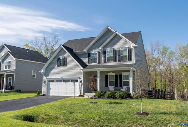 traditional-style house with a porch, an attached garage, a front lawn, and driveway