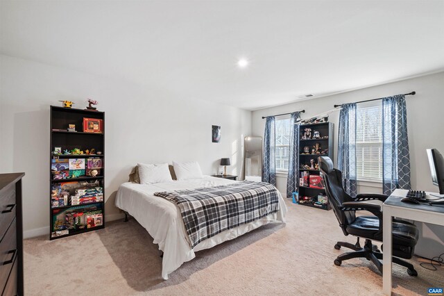 bedroom featuring light carpet and an office area