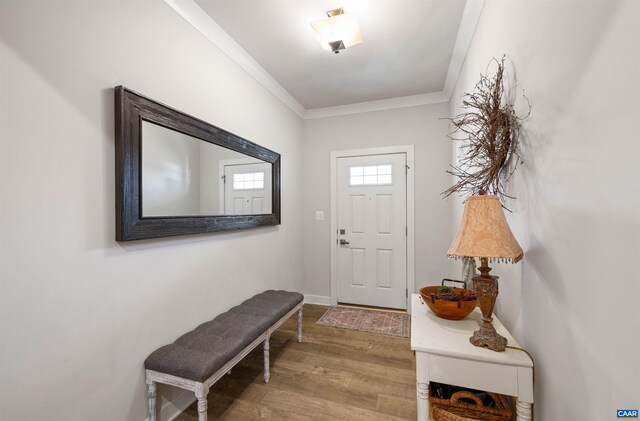 entryway with wood finished floors, crown molding, and baseboards