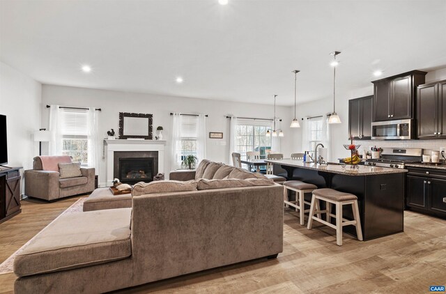 living area featuring light wood-type flooring, recessed lighting, and a glass covered fireplace