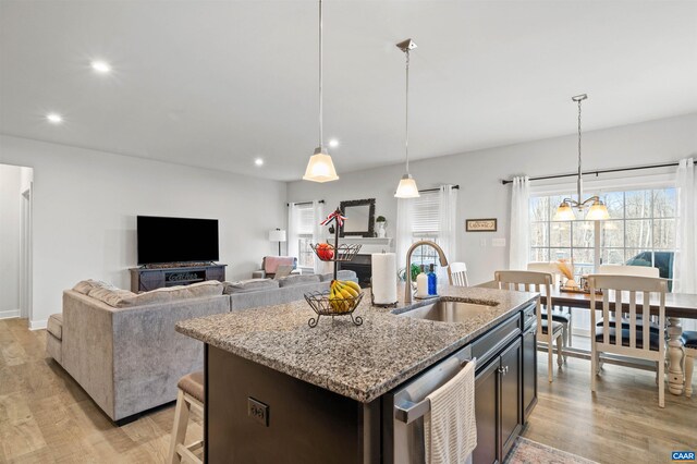 kitchen with a sink, light wood-style flooring, stainless steel dishwasher, recessed lighting, and light stone counters