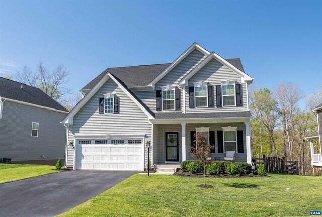 traditional-style home featuring a garage, fence, aphalt driveway, a front lawn, and a porch