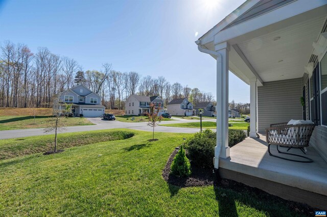 view of green lawn with covered porch and a residential view