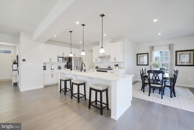 10909 Green Leaf Run, Spotsylvania, VA 22551 - kitchen featuring stainless steel appliances, dark wood finished floors, a breakfast bar area, an island with sink, and light countertops