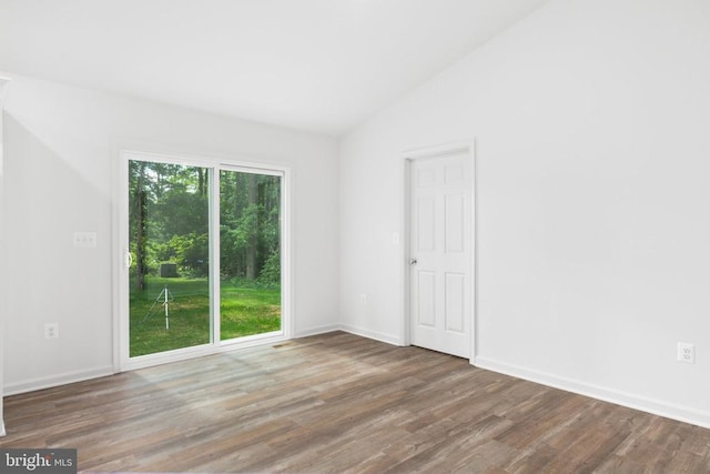 spare room with lofted ceiling, wood finished floors, and baseboards