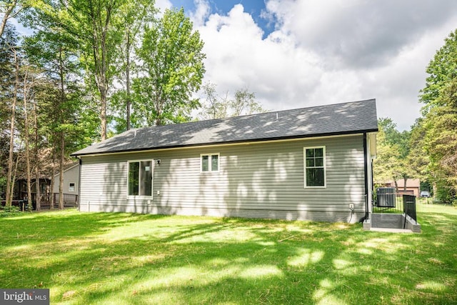 rear view of property featuring a yard and central air condition unit