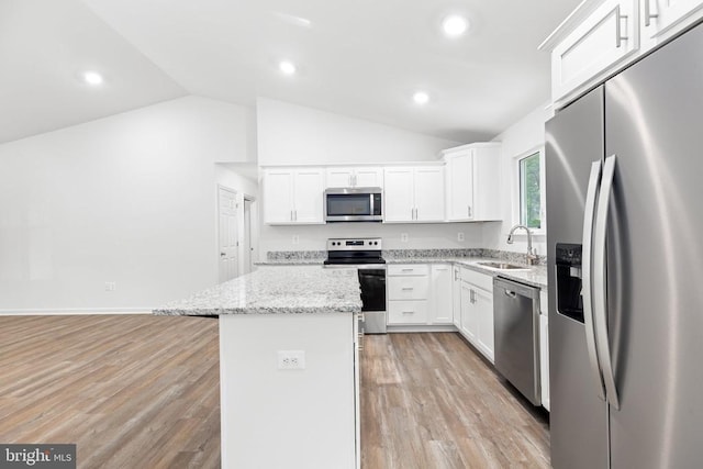 kitchen featuring a kitchen island, appliances with stainless steel finishes, white cabinets, and light stone counters