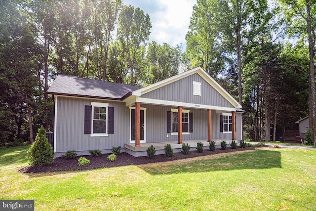 view of front of house featuring a porch, roof with shingles, and a front yard