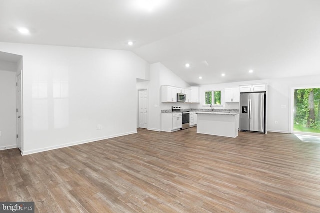 kitchen featuring stainless steel appliances, white cabinetry, open floor plan, light countertops, and a center island