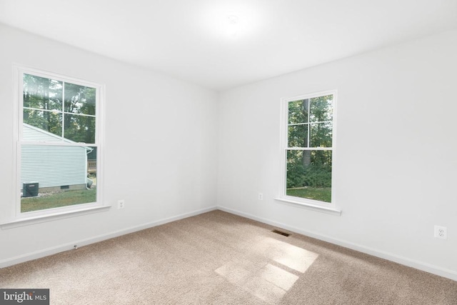 spare room featuring carpet, visible vents, and baseboards