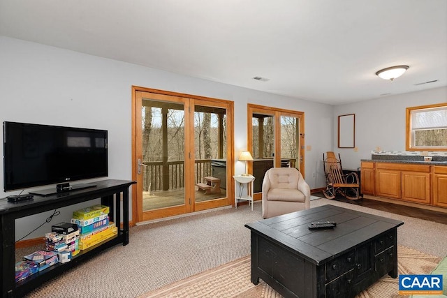 living area featuring light colored carpet, visible vents, and french doors